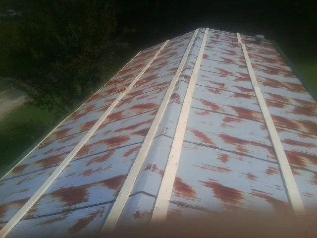Rusted metal roof panels with new wood purlins before replacement — Storm Damage Roof Repair in Rockwell City by Roofing Brothers