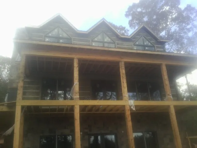 Dormers and porch framing on a large log home under construction — Roof Coating work by our crew in Rockwell City