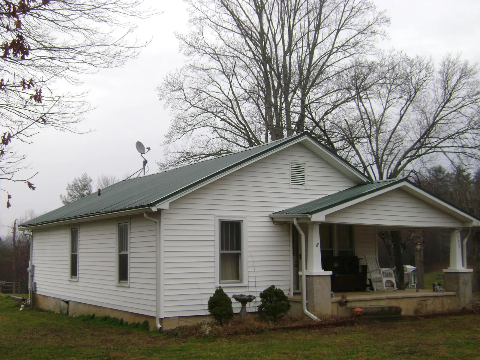 Green metal roof on a white bungalow with a side porch in Rockwell City