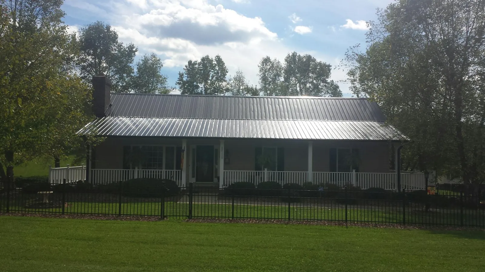 Gray metal roof on a brick ranch with a full width front porch — Gutter Guard Installation work by our crew in Rockwell City