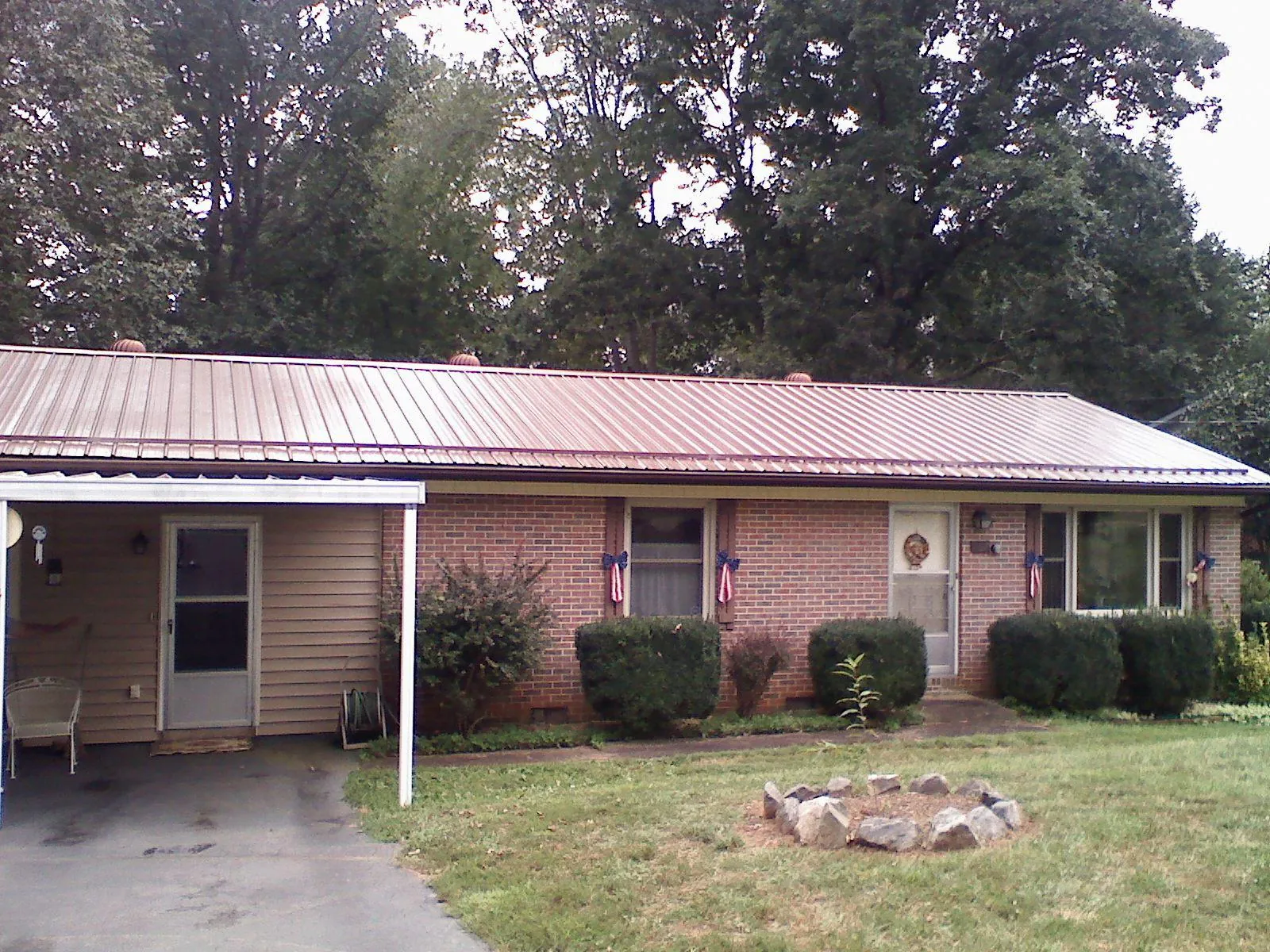 Bronze metal roof and carport on a brick ranch home — Roof Repair work by our crew in Rockwell City