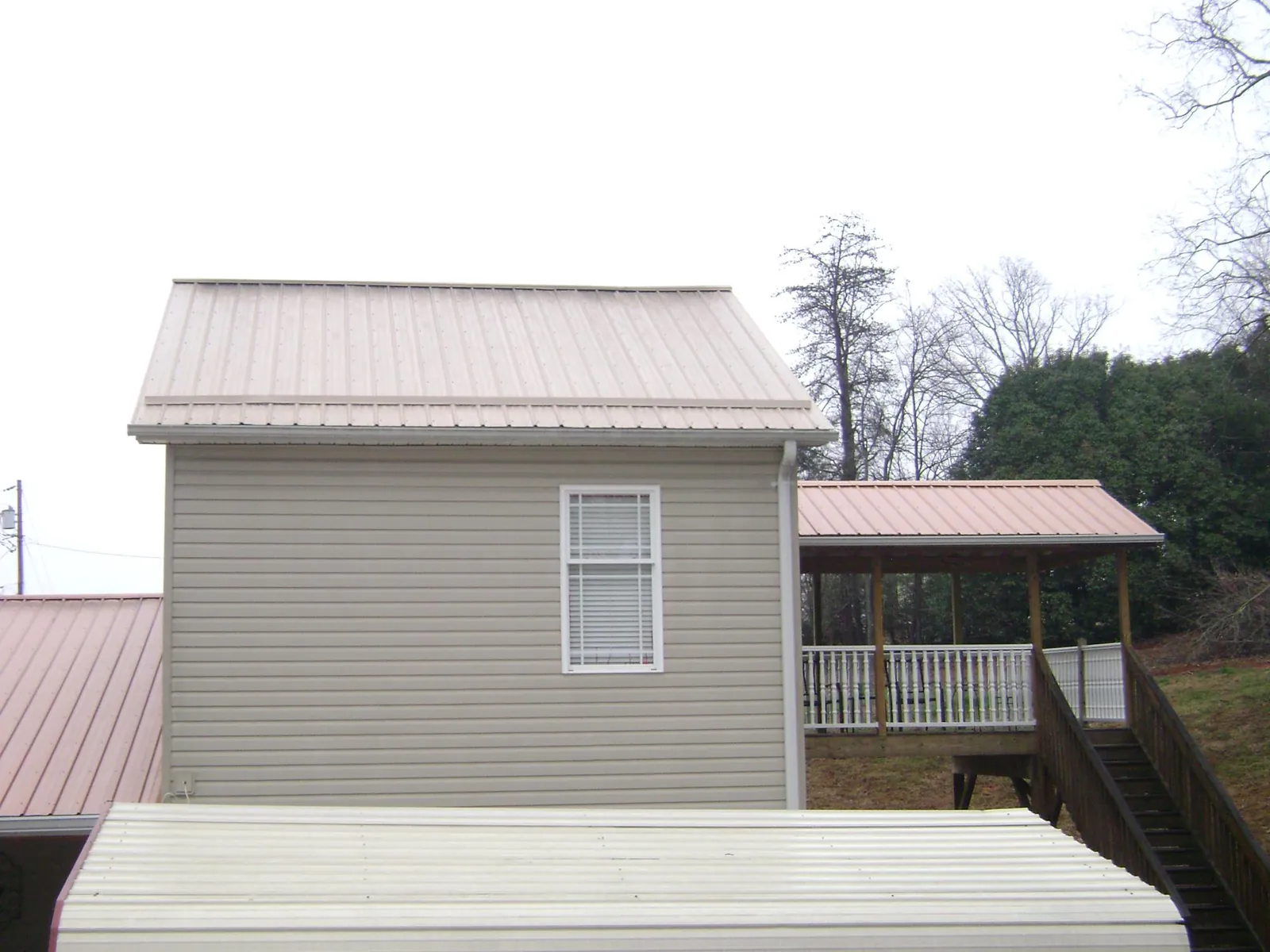 Tan metal roofs on a two story addition and attached porch, from a Roof Replacement job in Rockwell City