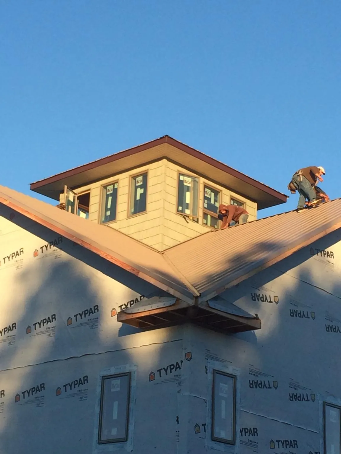 Roofers working around a rooftop cupola on a new metal roof at sunset — Roof Waterproofing in Rockwell City by Roofing Brothers